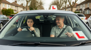 Young learner driver practicing with qualified driving instructor in UK car with L-plates